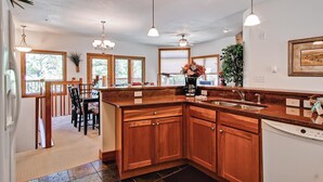 A kitchen with wooden cabinets, a large island, and pendant lighting. - Black Canyon Inn Unit F3 (Estes Park)