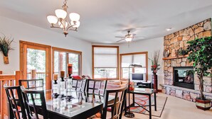 A dining area with a glass-top table and chairs, a ceiling fan, and a stone fireplace. - Black Canyon Inn Unit F3 (Estes Park)