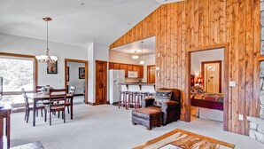 A spacious living area with a wooden accent wall, a dining table with chairs, a sofa, and a coffee table. - Black Canyon Inn Unit F10 (Estes Park)