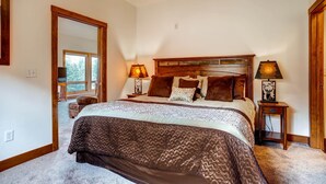 A bedroom with a large bed, two bedside tables, a mirror, and a window. - Black Canyon Inn Unit F10 (Estes Park)