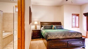 A bedroom with a wooden bed, a nightstand, a lamp, and a ceiling fan. - Black Canyon Inn Unit H1 Deluxe (Estes Park)