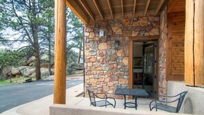 A stone building with a wooden porch, a table, and chairs. - Black Canyon Inn Unit H1 Deluxe (Estes Park)