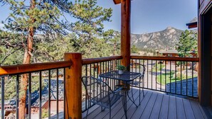 Una terraza de madera con una mesa y sillas, con vistas a un paisaje montañoso.