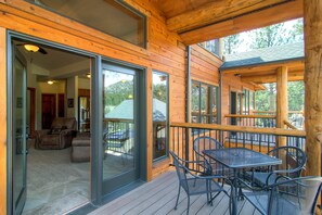 A wooden deck with a glass door leading to a living area, furnished with a sofa and a table. - Black Canyon Inn Unit H3 Deluxe (Estes Park)