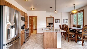 A modern kitchen with stainless steel appliances, wooden cabinets, a central island, and pendant lighting. - Black Canyon Inn Unit H4 Deluxe (Estes Park)