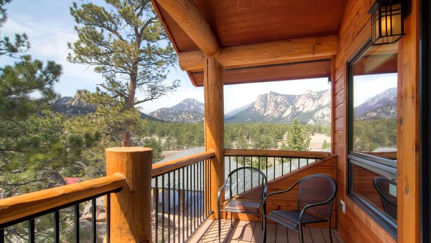 A wooden deck with two metal chairs, overlooking a mountainous landscape. - Black Canyon Inn Unit H4 Deluxe (Estes Park)