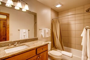 A bathroom with a double sink, vanity, toilet, and bathtub. - Black Canyon Inn Unit H4 Deluxe (Estes Park)