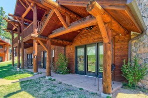 A log cabin with a covered porch, stone wall, and a view of the surrounding landscape. - Black Canyon Inn Unit A1/2 (Estes Park)