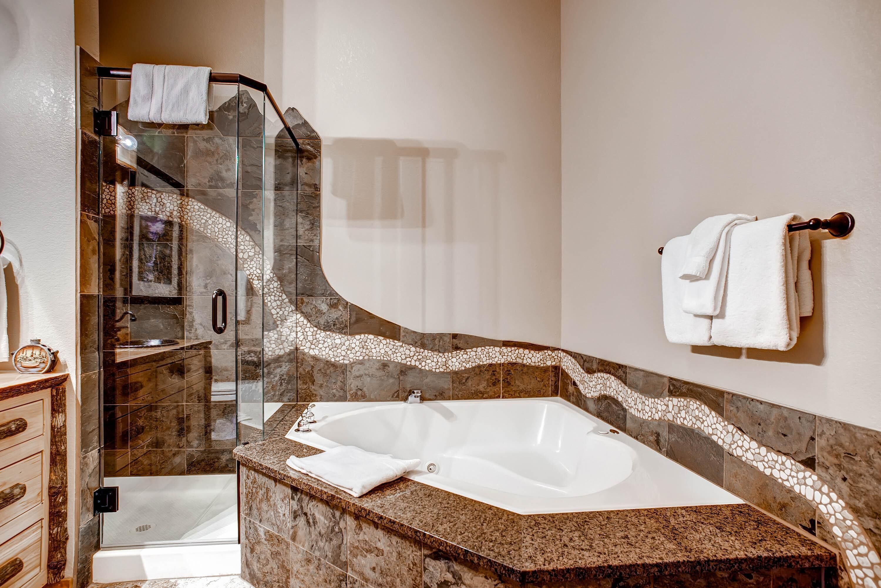Ein modernes Badezimmer mit einer gläsernen Duschkabine, einer freistehenden Badewanne und einer Marmorplatte.