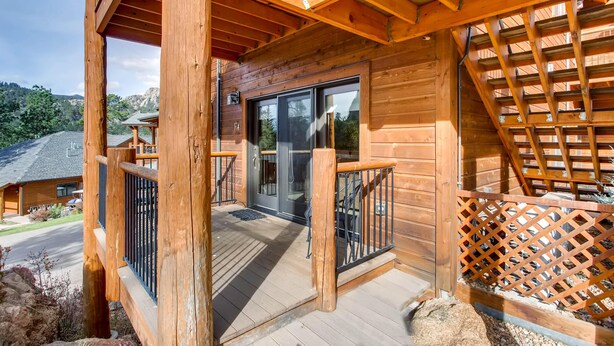 A wooden cabin with a balcony, a glass door, and a view of the surrounding landscape. - Black Canyon Inn Unit F4 (Estes Park)