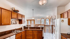 A spacious kitchen with wooden cabinets, a built-in dishwasher, and a large island. - Black Canyon Inn Unit F4 (Estes Park)