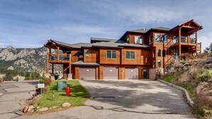 A large, multi-story wooden house with a garage, a covered porch, and a view of mountains. - Black Canyon Inn Unit F4 (Estes Park)