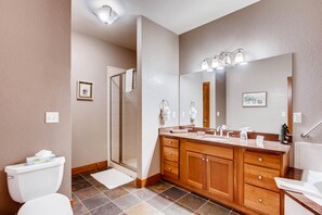 A modern bathroom with a shower, toilet, and vanity with a large mirror. - Black Canyon Inn Unit F1 Deluxe (Estes Park)
