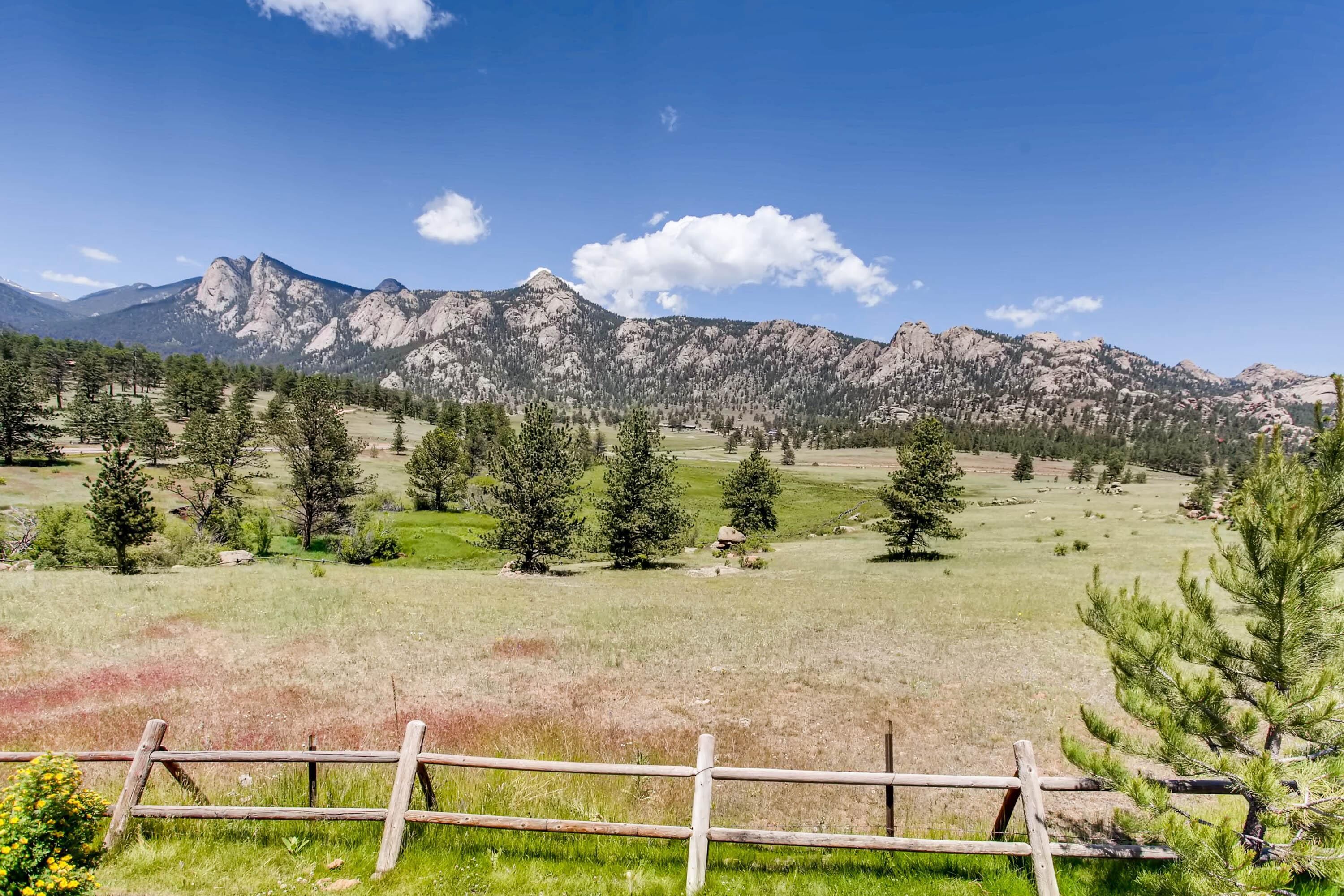 A mountainous landscape with a wooden fence in the foreground.