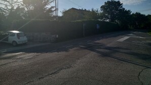 Una calle con un coche blanco estacionado al lado, una farola y una señal de tráfico indicando direcciones.