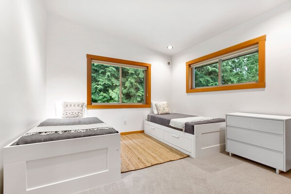 A bedroom with two beds, a dresser, and two windows with wooden frames. - Bellingham Modern Lodge-4bd 4 bath hot tub barrel sauna- perfect adventure house (Bellingham)
