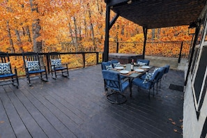 Un patio al aire libre con suelo de madera, sillas tapizadas en azul y una mesa lista para comer.