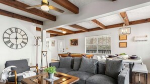 Ein Wohnzimmer mit einer Couch, einem Couchtisch, einer Uhr und einem Essbereich mit Tisch und Stühlen.