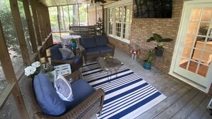 A covered porch with wicker furniture, a ceiling fan, and a TV mounted on the wall.