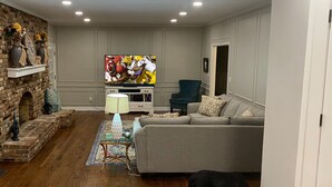 A living room with a fireplace, a television, a sofa, and a dog eating from a bowl.