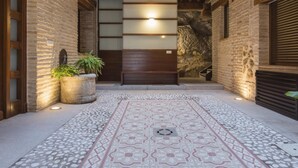A covered outdoor area with a patterned floor, stone walls, and a wooden bench. - San Cipriano. Apartment with garage included (Toledo)
