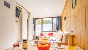 Un coin repas chaleureux avec une table dressée pour deux, agrémenté d’un panier de pain, d’une bouteille d’huile et d’une nappe en forme de cœur.