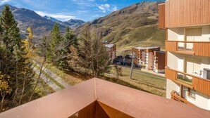 Un bâtiment moderne à plusieurs étages, doté d’une façade en bois, qui se dresse sur un fond de paysage montagneux.