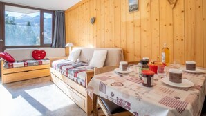 Une pièce chaleureuse avec un mur en bois, un lit, un banc et une table sur laquelle sont disposés des aliments pour le petit-déjeuner.