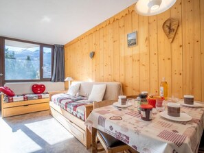 A cozy room with a wooden wall, a bed, a bench, and a table with breakfast items.