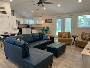 Relax in this stylish living room with a sofa, ottoman, and armchair, plus a kitchen area with oven.