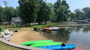 Une zone au bord du lac, avec une jetée en béton, des kayaks et une rangée de chaises blanches.