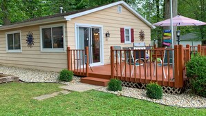 Une petite maison avec une terrasse, un barbecue et une boîte aux lettres.
