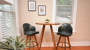 A room with two black leather bar stools, a wooden table, and a potted plant.