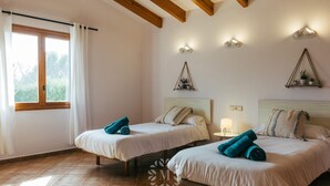 Una camera da letto con due letti, travi in legno al soffitto, una finestra con tende e luci a parete.