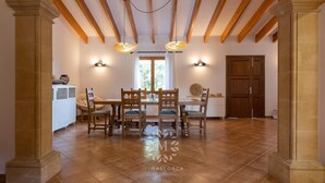 Un'ampia sala da pranzo con soffitto alto, travi in legno e un'ampia arcata.