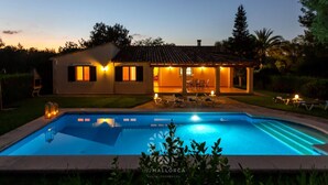 Una casa a due piani con piscina, area salotto esterna e patio.