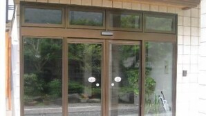 A building entrance with a glass door and a small sign above it. - Tokiwa Ryokan (Nikko)