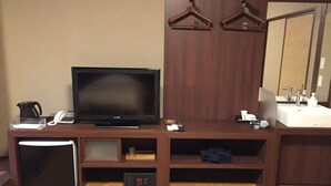 A hotel room with a flat-screen TV, a coffee maker, a phone, a remote control, a sink, and a mirror. - Tokiwa Ryokan (Nikko)