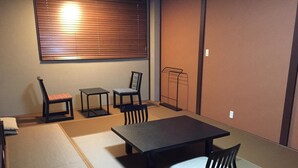 A tatami mat room with a low table, two chairs, and a bench. - Tokiwa Ryokan (Nikko)
