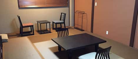A tatami mat room with a low table, two chairs, and a bench.