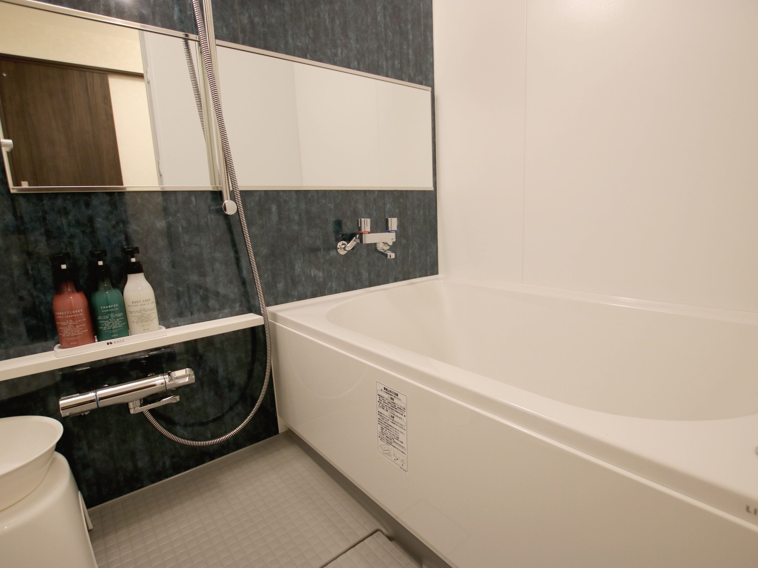 Une salle de bain moderne avec une baignoire blanche, une douche intégrée et un meuble-lavabo avec des articles de toilette.
