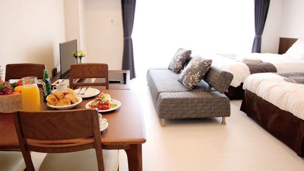 Een hotelkamer met een ontbijt gedekte eettafel, een sofa en twee bedden.