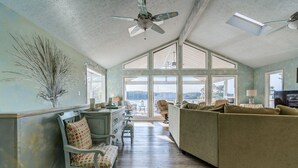 Un salon spacieux avec un plafond haut, de grandes fenêtres et une vue sur l’extérieur.