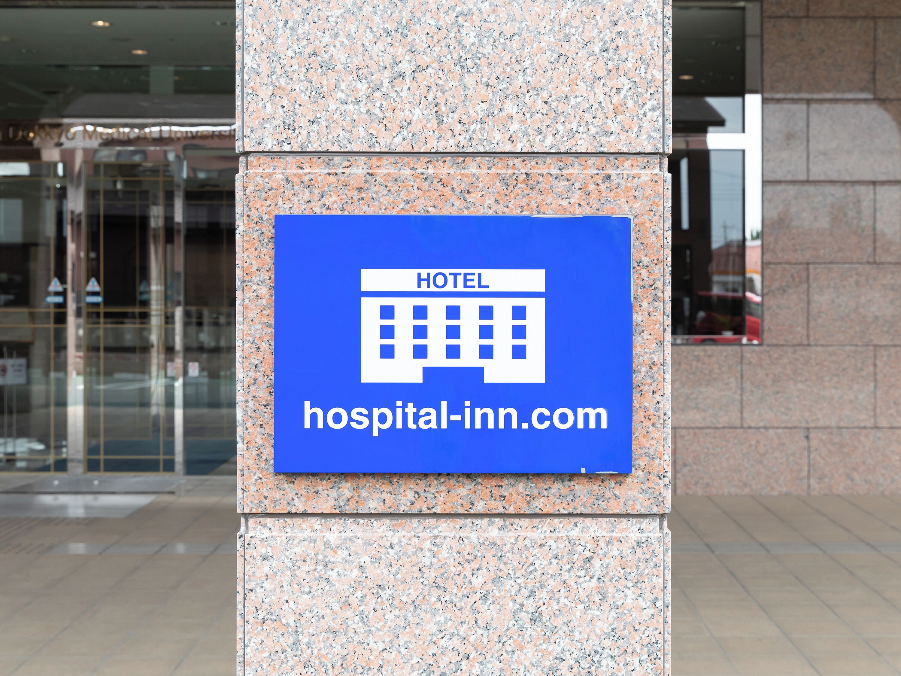 A sign on a building indicating a hotel with a website address.