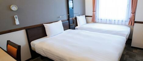 Una habitación de hotel con dos camas, una mesita de noche, una lámpara, una ventana con cortinas y un termostato en la pared.