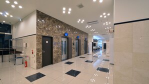 Eine moderne Hotelhalle mit Marmorwand, Aufzügen und einem sauberen, gefliesten Boden.