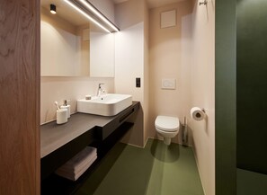 Ein modernes Badezimmer mit einem weißen Waschbecken, einer Toilette und einem Spiegel.