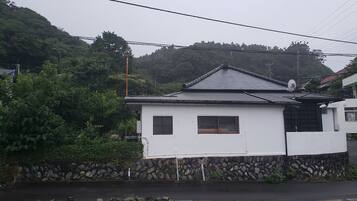 A white building with a tiled roof, a stone base, and a small window.
