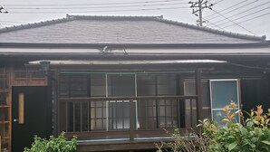 Une maison traditionnelle japonaise dotée d’une terrasse en bois, d’une porte coulissante et d’un petit jardin.