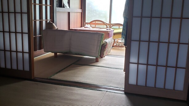 Une pièce de style japonais traditionnel, avec un sol recouvert de tatamis, un lit bas en bois et des portes coulissantes en papier de riz (shoji).
